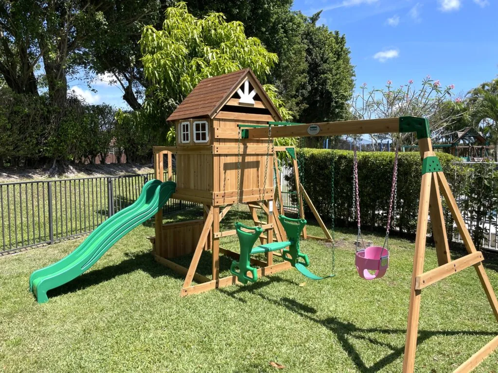 Completed backyard swing set with playhouse and slide