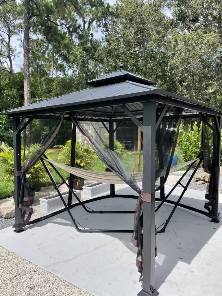 Finished metal gazebo with a hanging swing and mesh curtains on a patio