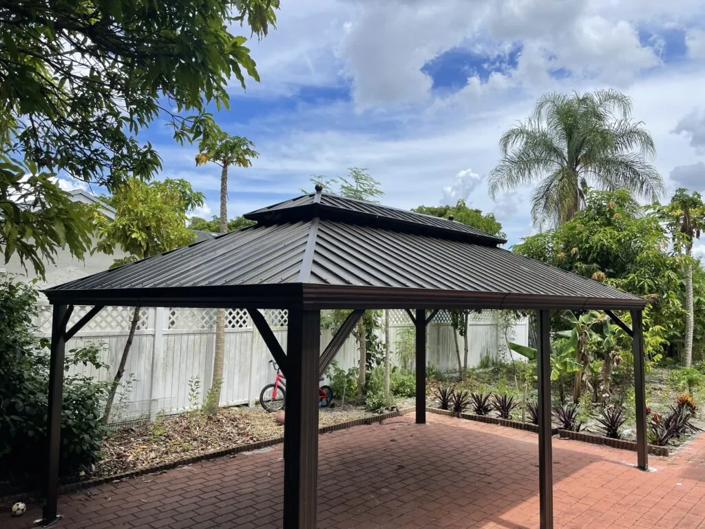 Completed dark metal gazebo covering a brick backyard patio