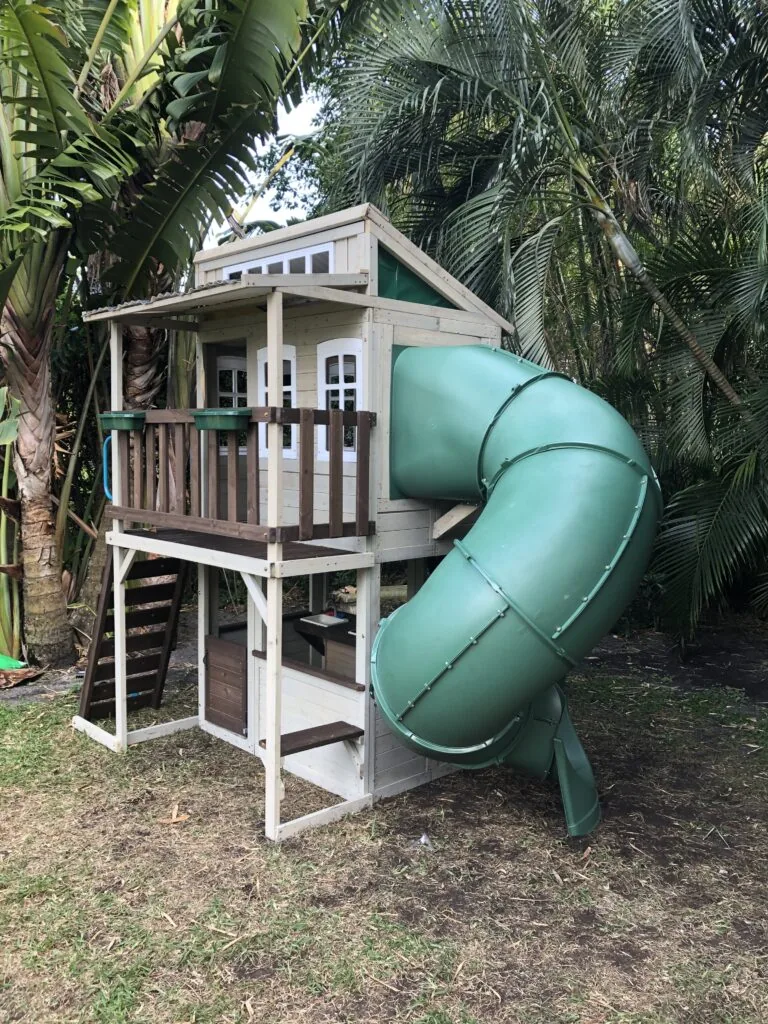Wooden playhouse with curved tube slide