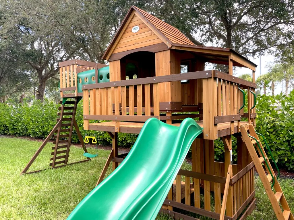 Wooden playset deck with green slide and climbing ladder