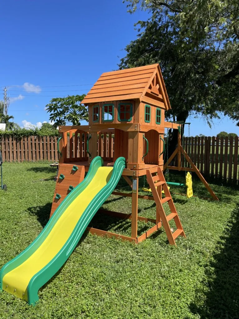 Wooden playhouse with green slide built by David